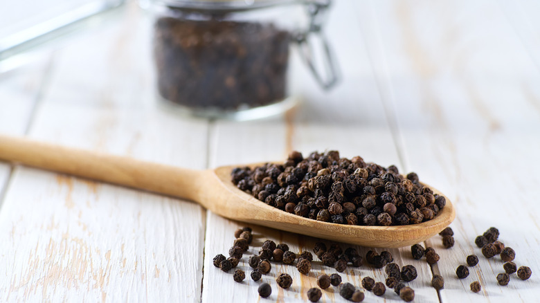 black peppercorns on wooden spoon