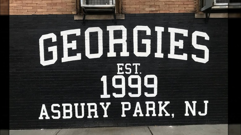 Georgies Bar mural painted with white letters on black background on brick wall
