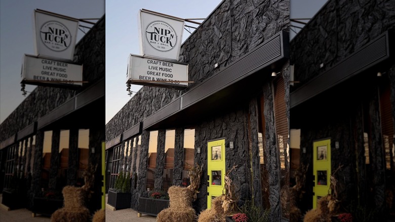 Exterior of Nip n Tuck Bar & Grill with white sign over doorway