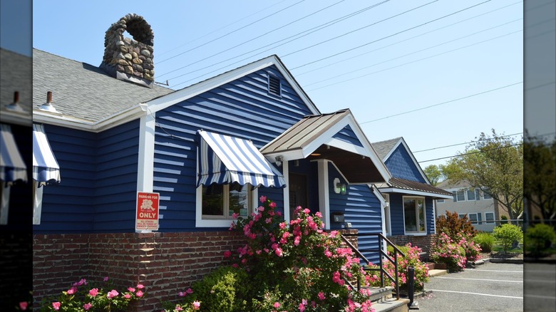 Exterior of the Ark Pub and Eatery in small, cozy house with awnings, flowers, and stone chimney