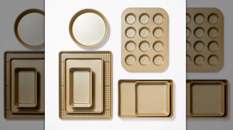 A gold cooling rack, a muffin tin, a square baking pan, a round baking pan, and a loaf pan