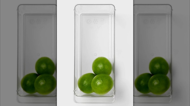 Clear fridge organizer bin with three limes in it
