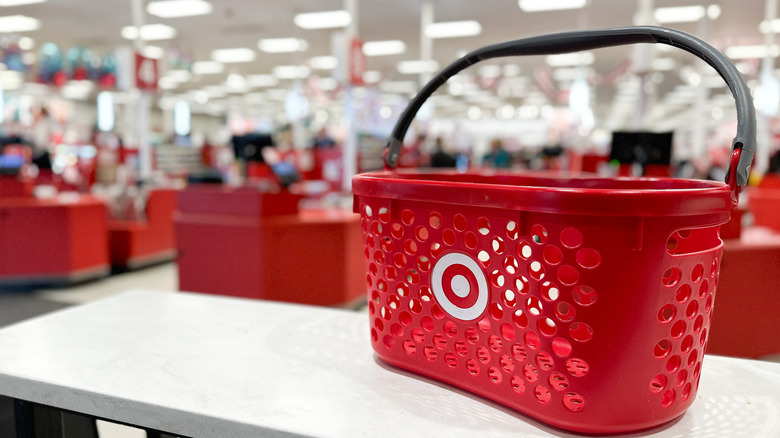 Red Target shopping basket on a flat white table with checkout lanes in the background