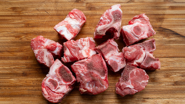 Raw chunks of ox tails on a wooden board