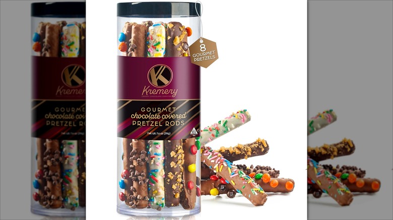 Clear jar with gourmet chocolate-covered and candy-coated pretzel rods on a white background.