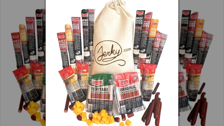 Meat and cheese sticks surrounding gift bag on a white background.