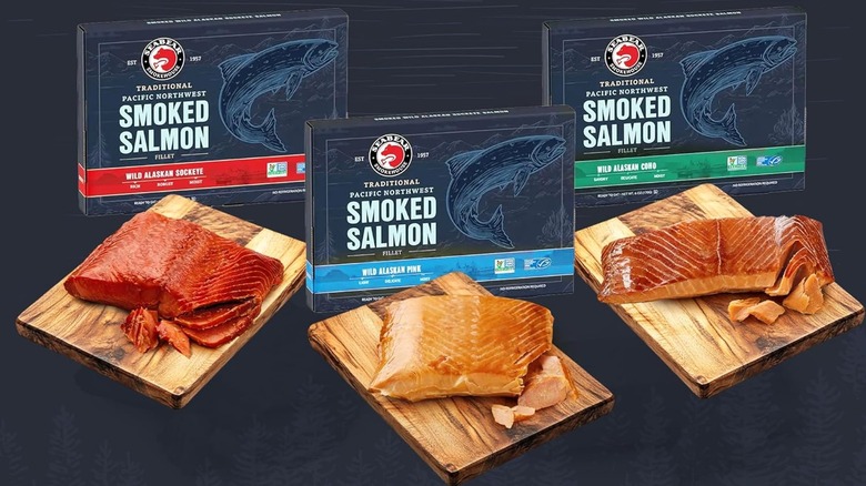Three filets of smoked salmon on wood boards in front of smoked salmon packages.
