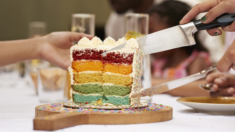 Cut rainbow-colored cake on a wood board