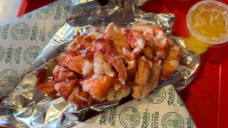 Red's Eats lobster roll wrapped in foil served with melted butter on a red food tray