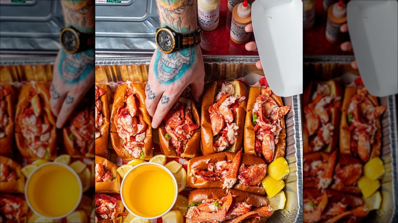 Hand reaching down to retrieve a lobster roll from an aluminum pan from The Highroller Lobster Co.