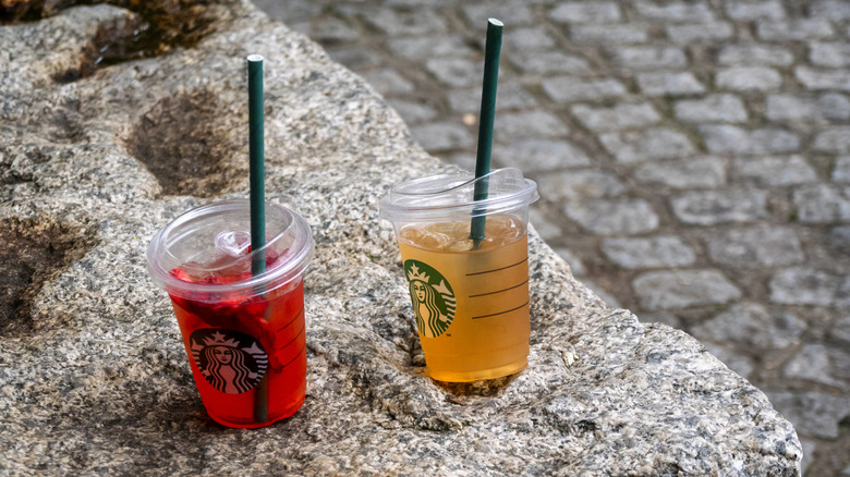 Two abandoned Starbucks Refreshers left on a stone bench