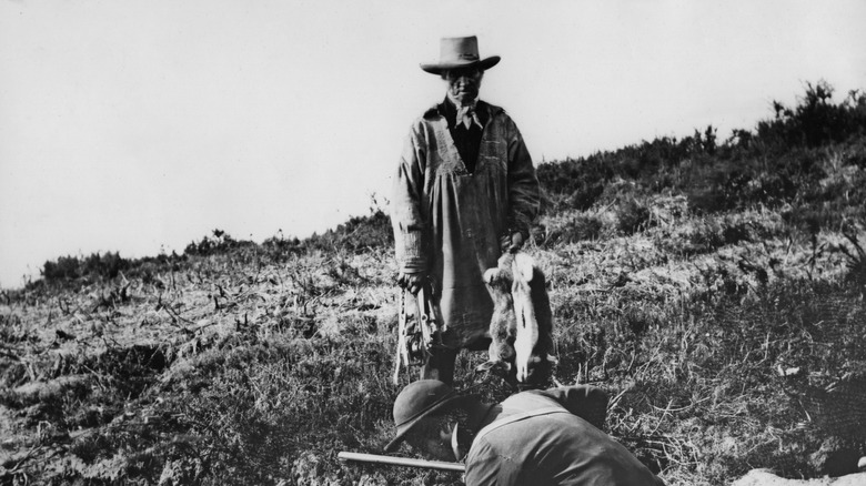 Old photo of gamekeepers collecting rabbits they hunted