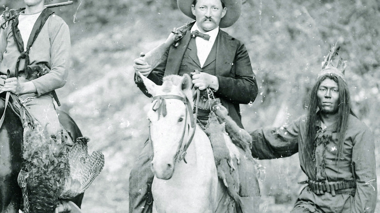 Three men hunting with one holding a batch of hunted squirrels
