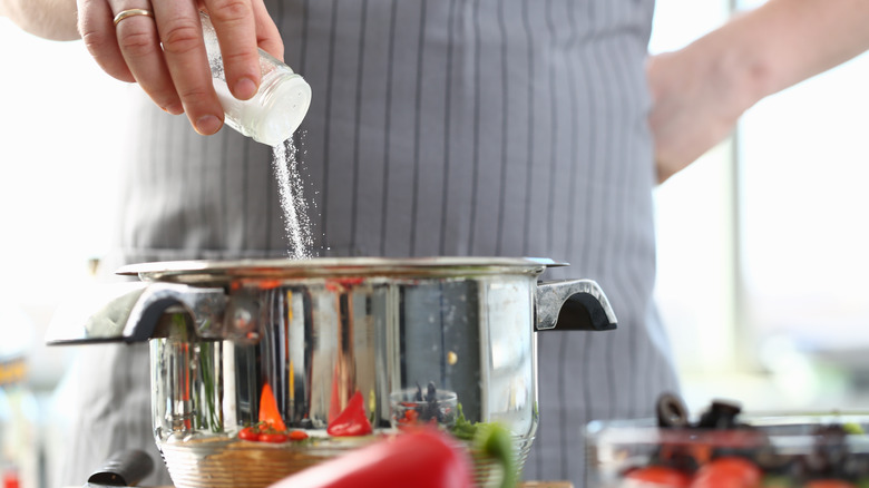 Person adding salt to a pot
