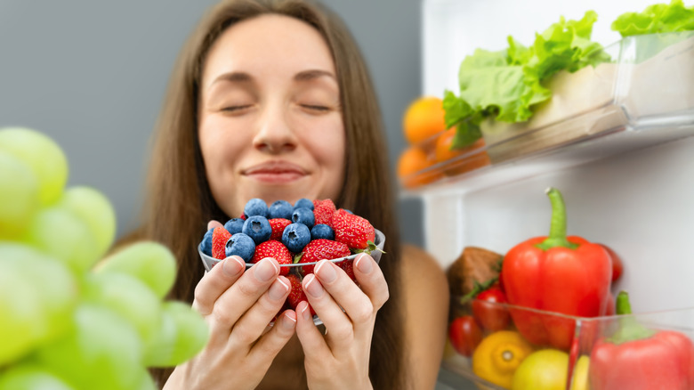 Woman smelling a bowl of blueberries