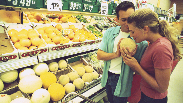 Couple chooses a cantaloupe by smelling one in produce section
