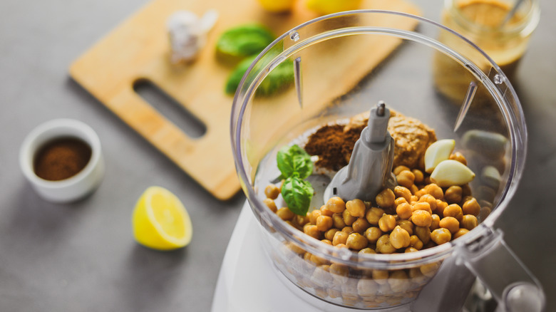 Chickpeas, garlic, tahini, and spices in kitchen blender to prepare hummus