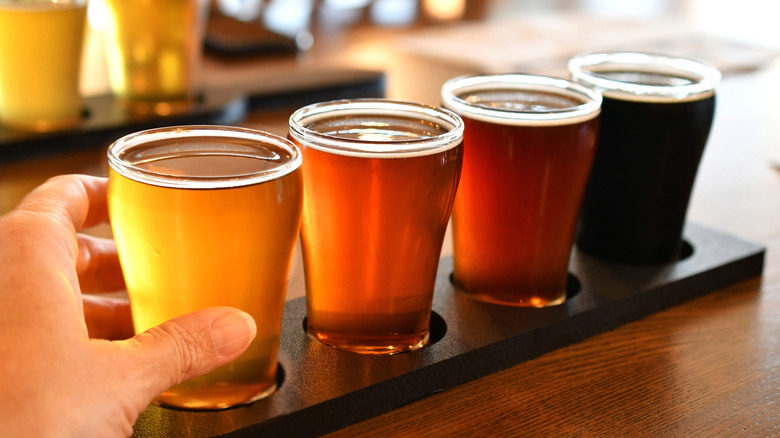 Flight of four small beers on a wooden serving tray.