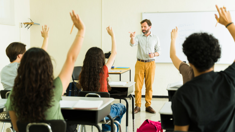 Classroom of students with their arms raised.