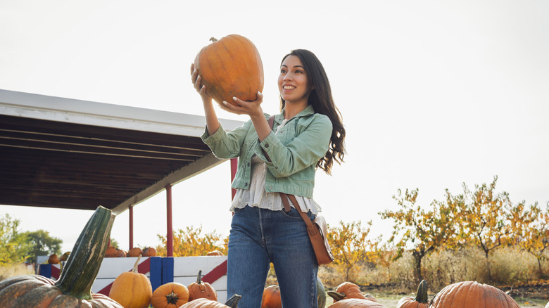 Woman holding up pumpkin at farm store