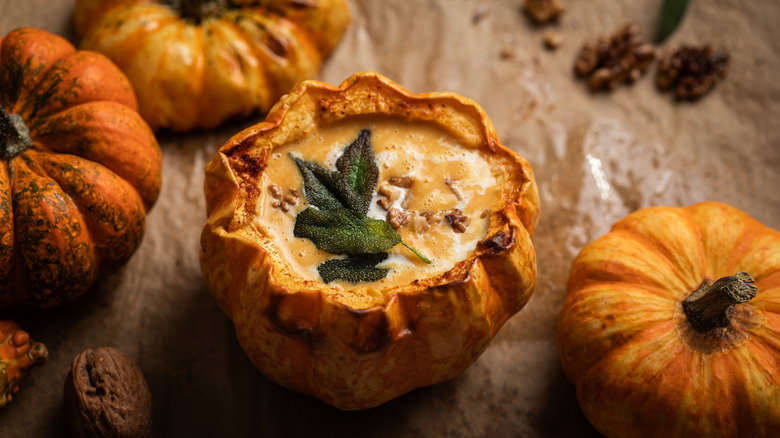 Pumpkin bowl filled with soup topped with crispy sage leaves