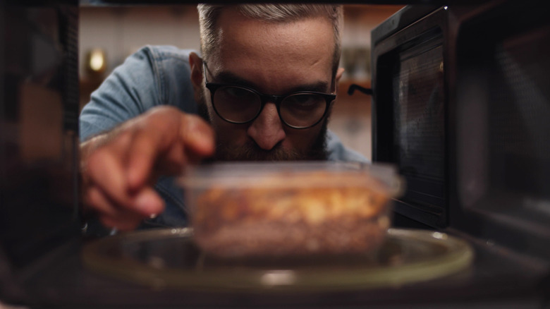 A man placing food in the microwave