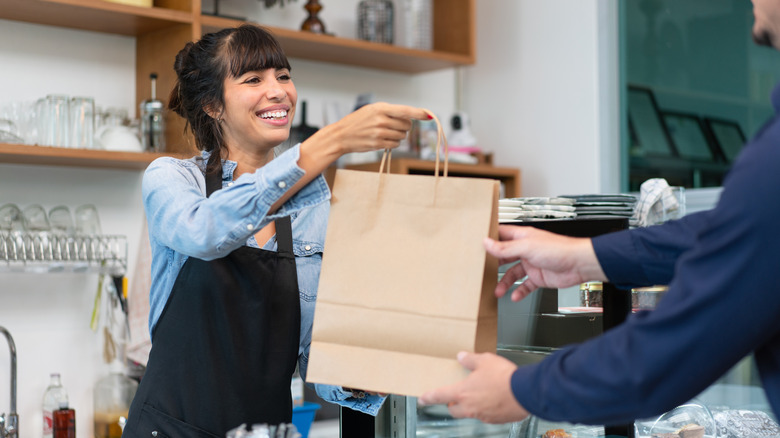 Cafe employee handing takeout order to customer