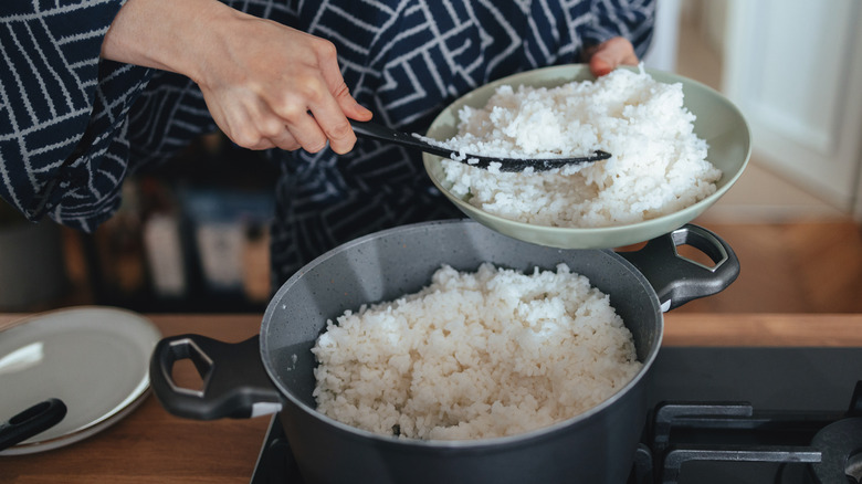 Person scooping rice from a pot onto a plate