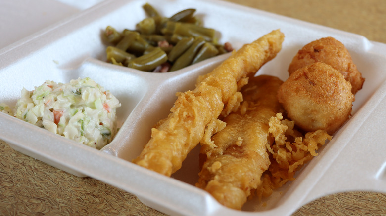 Coleslaw, green beans, and fish in a to-go box
