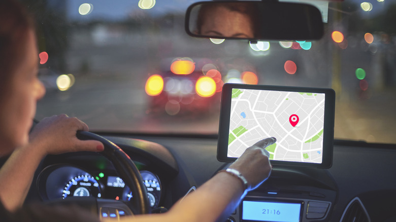 A woman in the car pointing to the GPS map