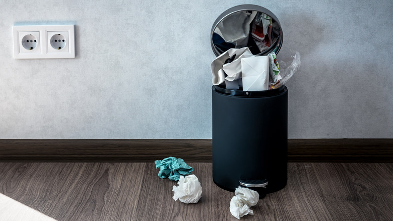Trash in kitchen overflowing with paper