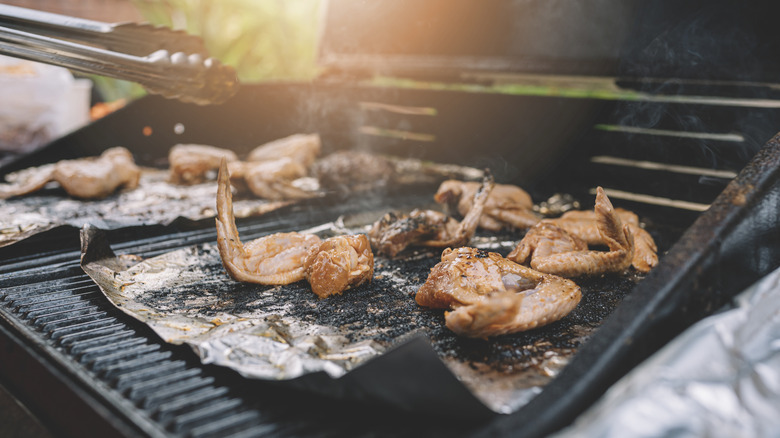 Close-up barbecue chicken wing on barbecue grill on top of the foil