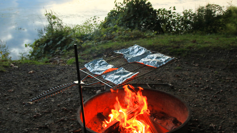 Cooking foil packs over an open fire at a campsite