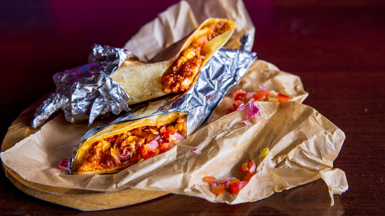 Burritos filled with meat and vegetables wrapped in aluminum foil