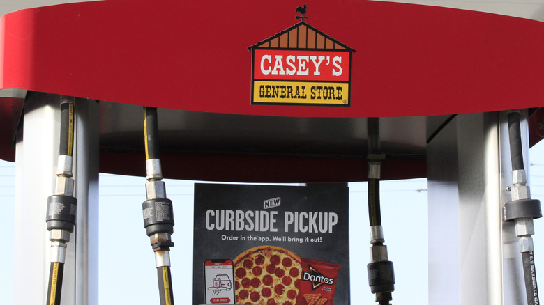 A NASCAR driver having a slice of Casey's pizza in front of his car and a Casey's display