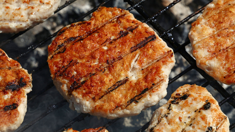 Turkey burgers cooking on a grill.