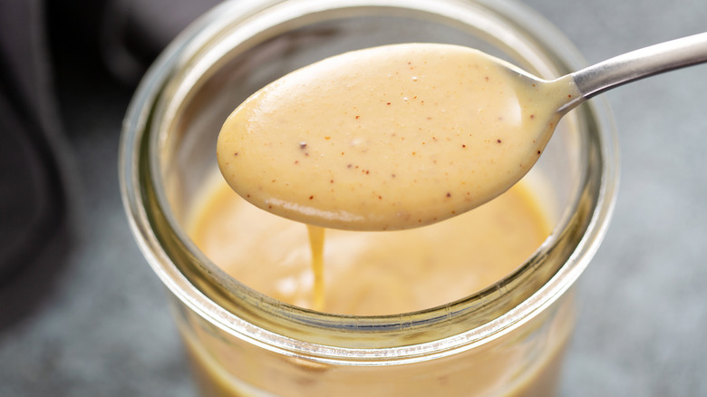Spoon getting salad dressing out of a jar