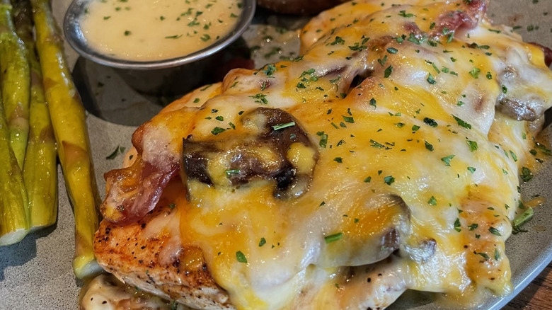 Closeup of Outback's Alice springs chicken with cheese, mushrooms, bacon, honey mustard sauce, and asparagus