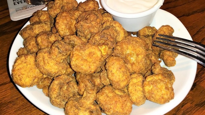 Outback's fried Sydney shrooms on a white plate with a fork and some dipping sauce