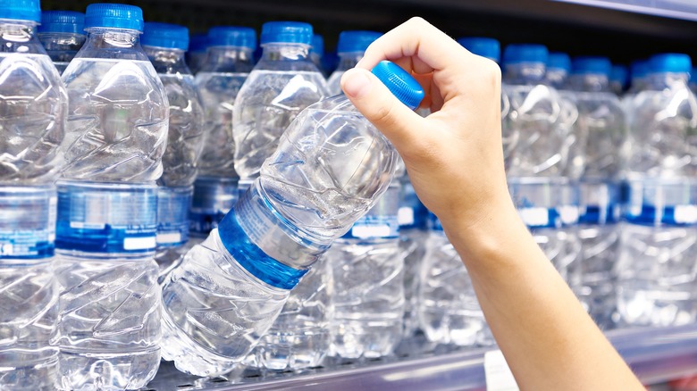 Person grabbing a bottle of water off store shelf