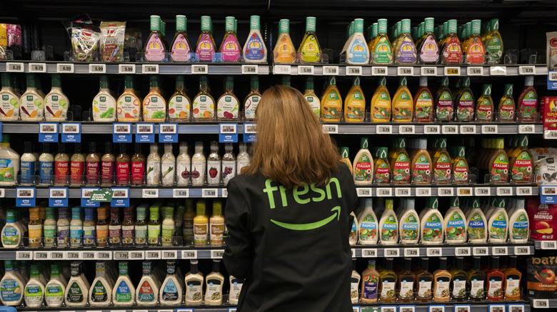 Person standing in front of store shelves stocked with assorted salad dressings