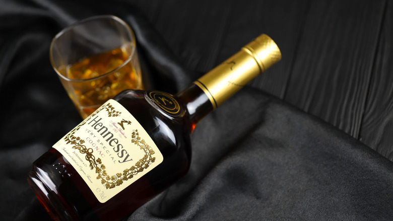 A bottle of Hennessy cognac laying next to a glass