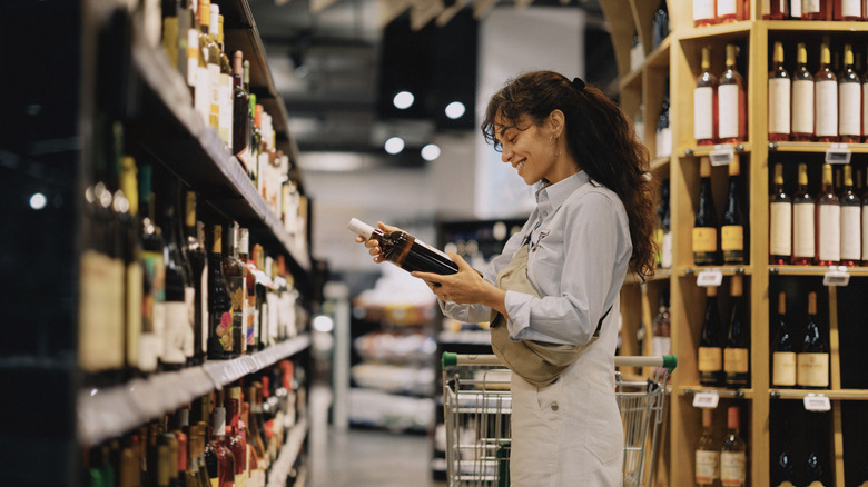 A woman examining a bottle of liquor at the store
