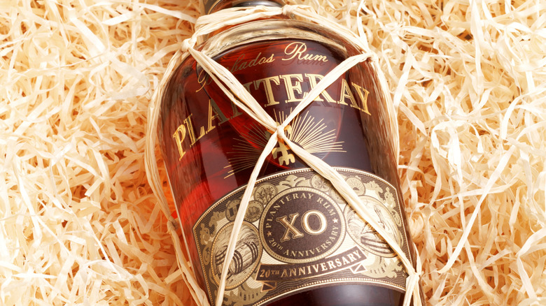 A bottle of Planteray rum set among straw