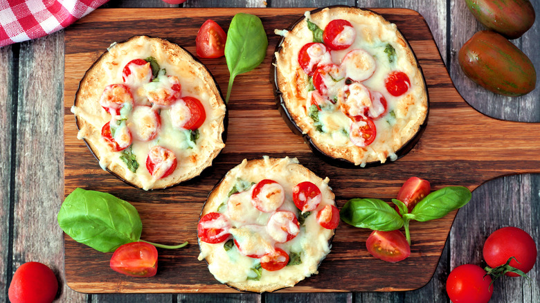 Eggplant pizzas on a wooden serving board with garnishes