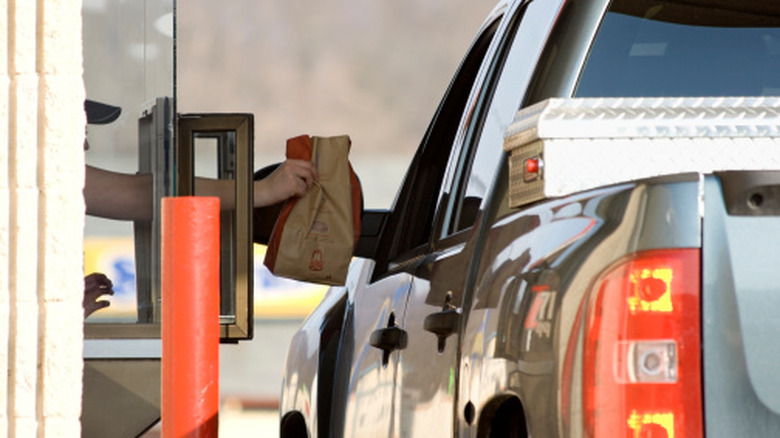 Arby's worker handing a takeout order to a customer at the drive thru