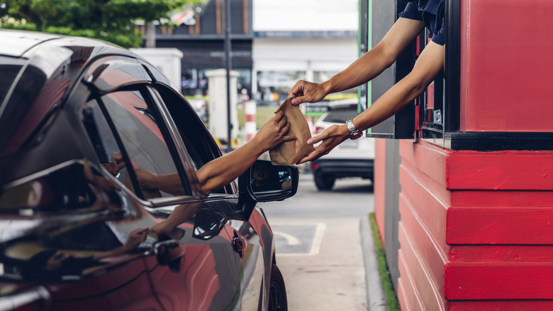 Employee passing a customer their food at the drive thru