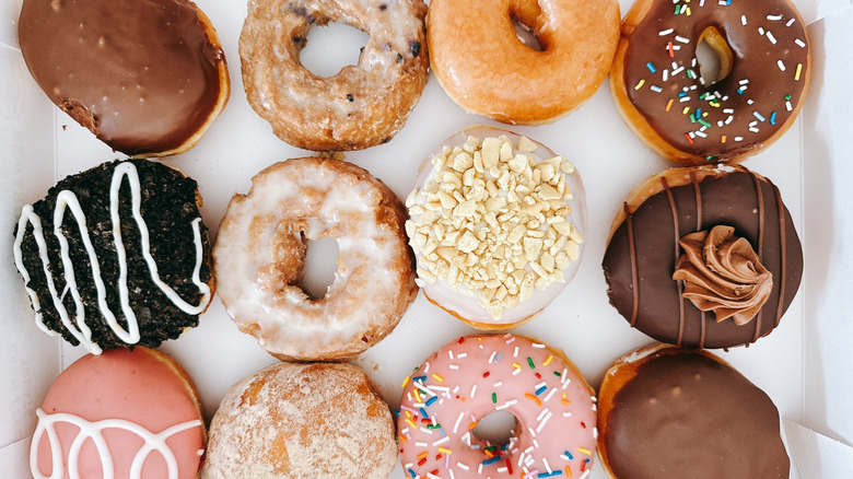 A dozen assorted Krispy Kreme Doughnuts in box on wooden table