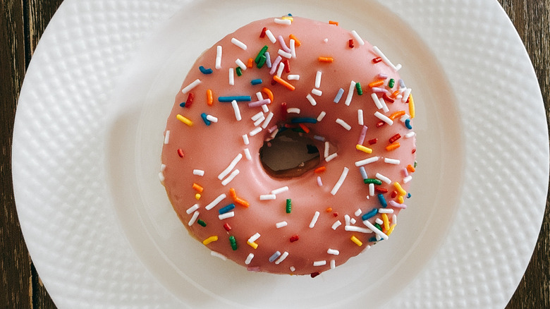 Krispy Kreme Strawberry Iced with Sprinkles Doughnut on white plate