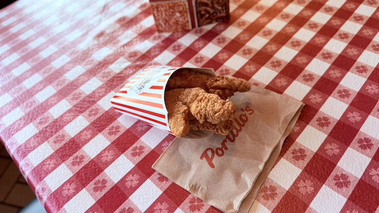 Container of chicken tenders on checkered tablecloth